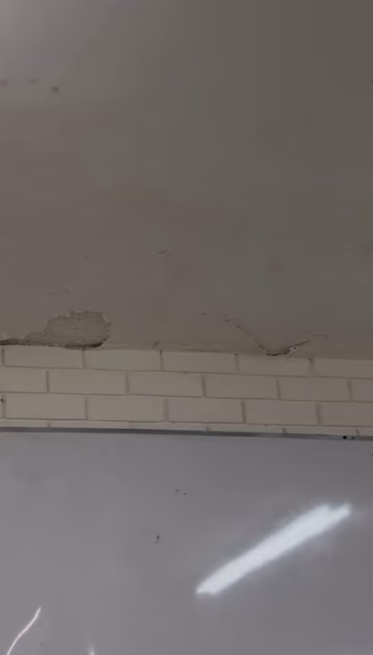 Grietas en el techo del aula 3301 y un trozo de aplanado desprendido cerca del borde con la pared de ladrillo.