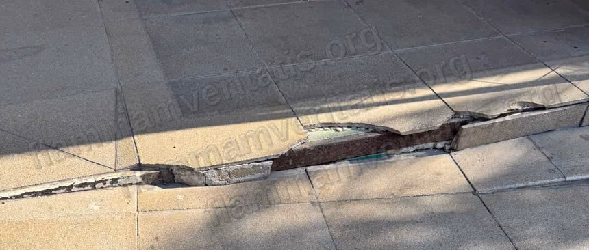 Losa de concreto partida en el borde de una rampa-escalera de acceso al Edificio 7, con una varilla metálica oxidada expuesta a lo largo de toda la grieta.